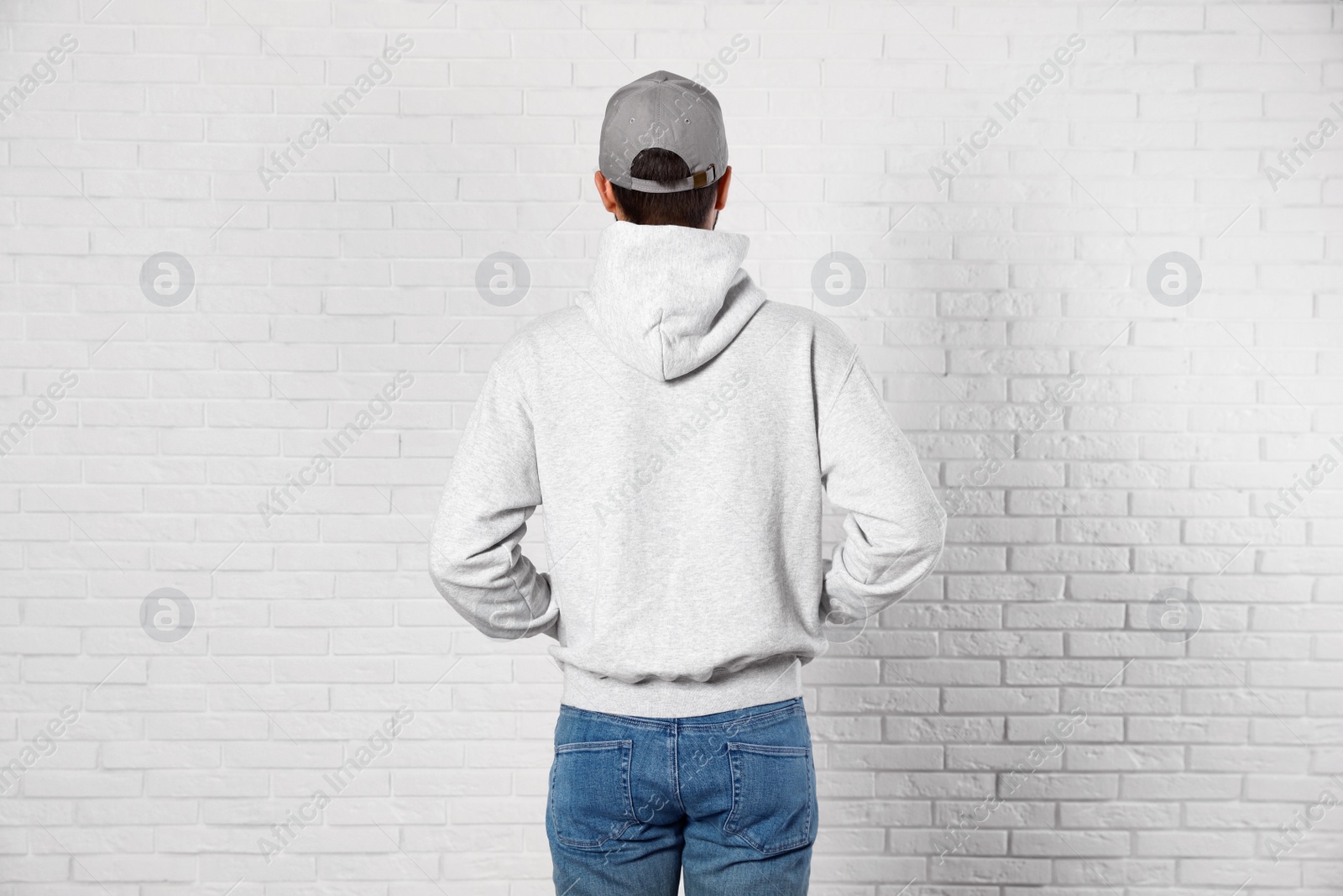 Photo of Young man in sweater at brick wall. Mock up for design