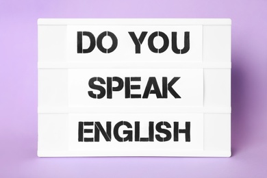 Photo of Stand with question Do You Speak English on violet background