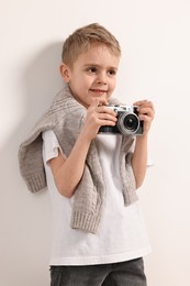 Photo of Fashion concept. Stylish boy with vintage camera on white background