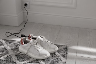 Shoes with electric dryer on rug indoors