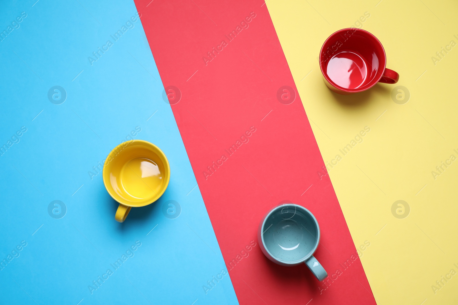 Photo of Different bright ceramic cups on color background, flat lay