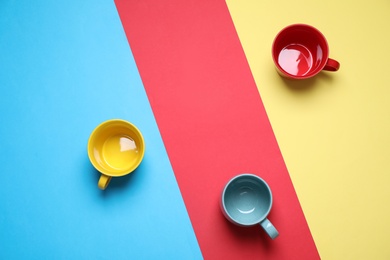 Photo of Different bright ceramic cups on color background, flat lay