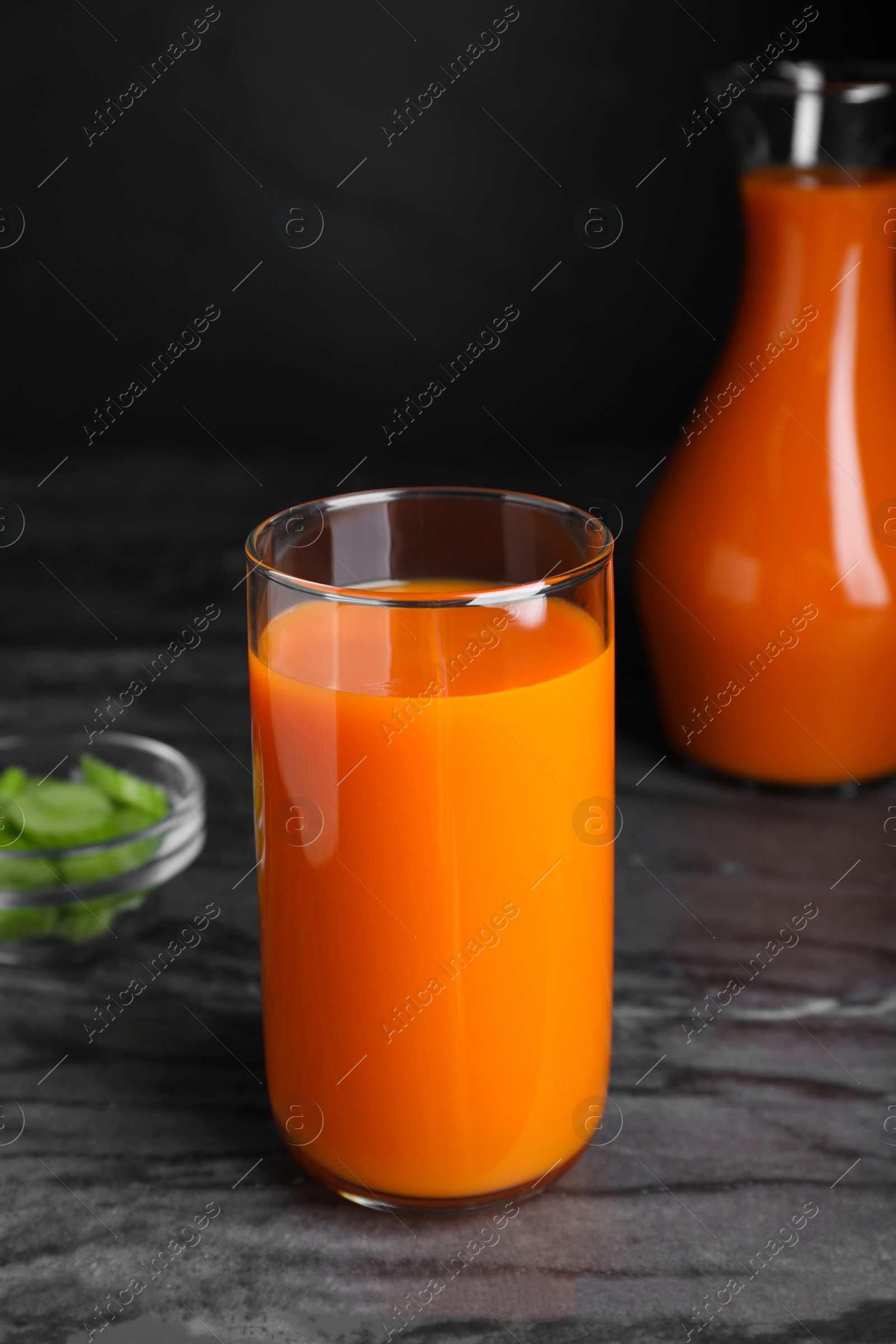 Photo of Tasty refreshing carrot juice on black marble table