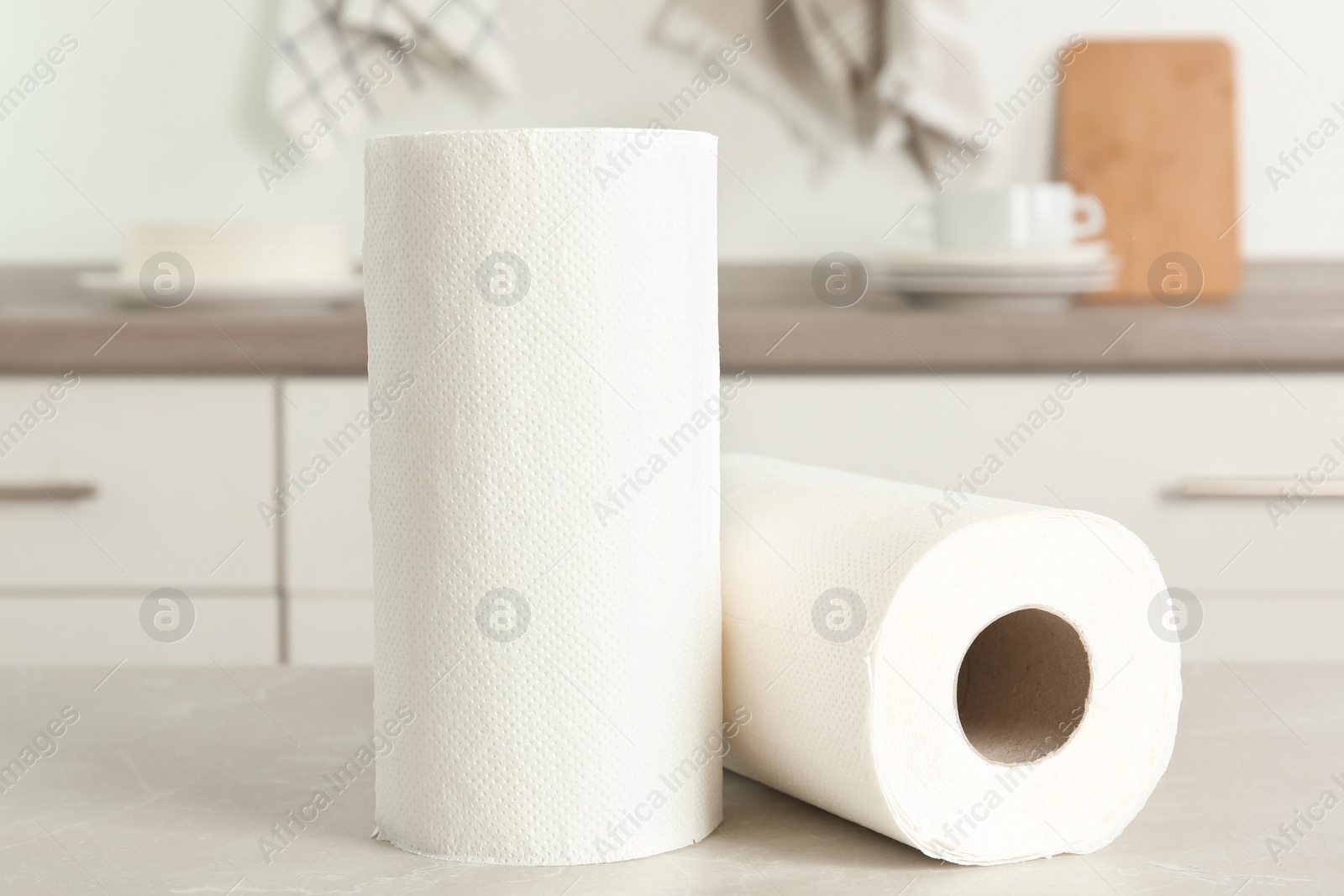 Photo of Rolls of paper towels on light grey marble table in kitchen