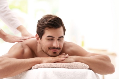 Photo of Handsome young man receiving back massage in spa salon