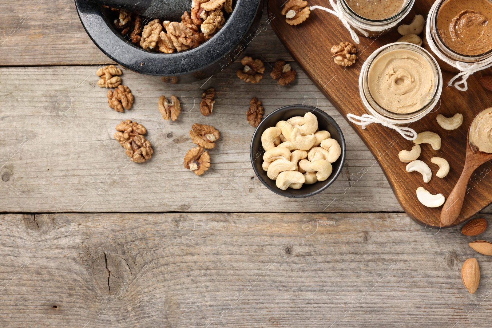 Photo of Making nut butters from different nuts. Fat lay composition with space for text on wooden table