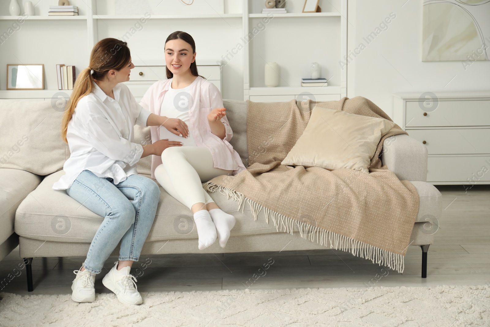 Photo of Doula taking care of pregnant woman on sofa at home. Preparation for child birth