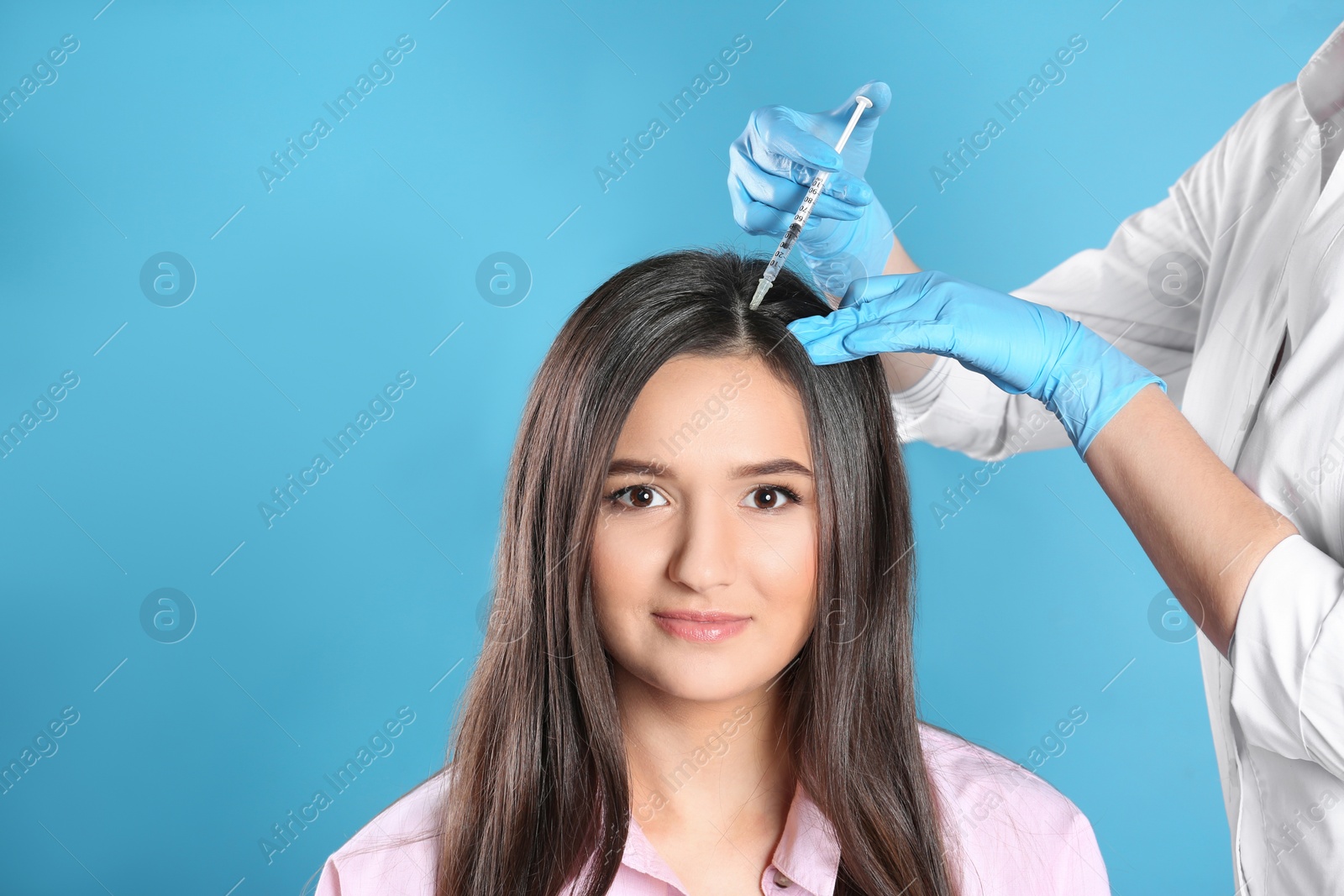 Photo of Young woman with hair loss problem receiving injection on color background