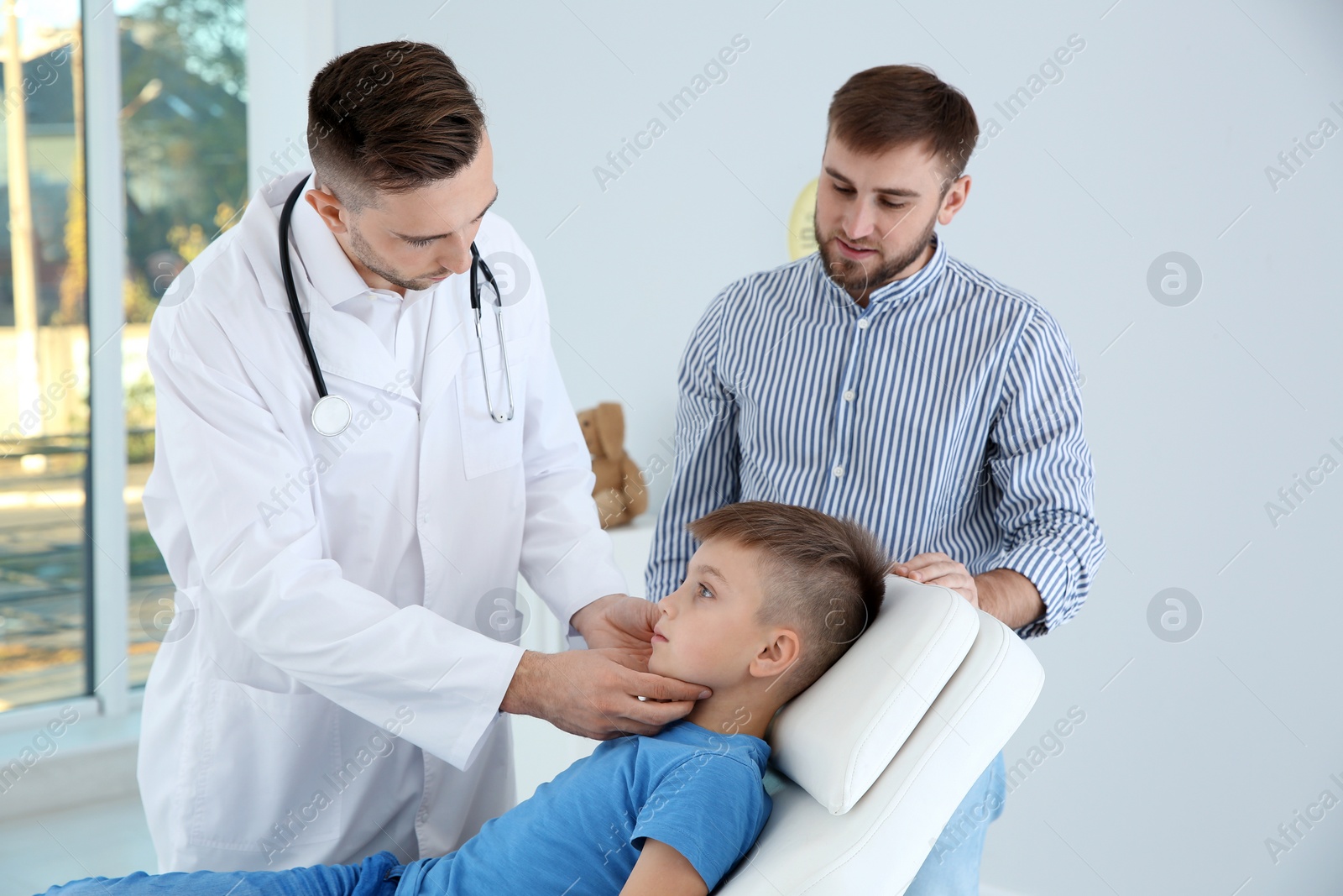 Photo of Father and son visiting pediatrician. Doctor working with patient in hospital