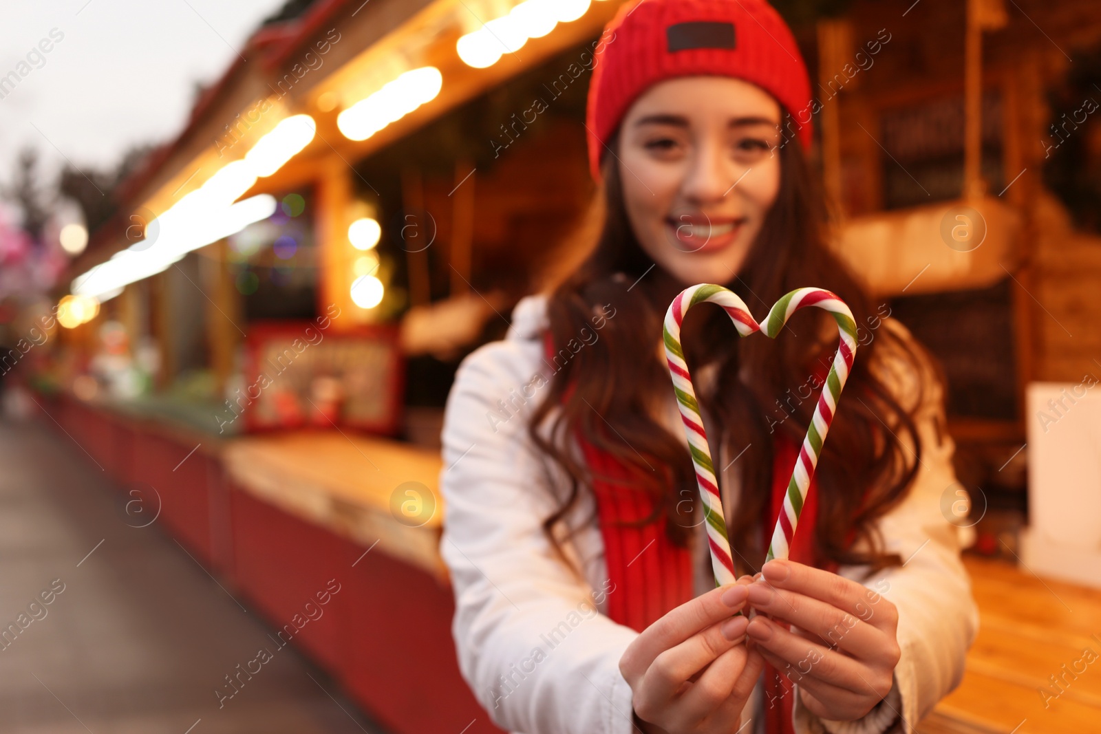 Photo of Young woman spending time at Christmas fair, focus on candy canes. Space for text