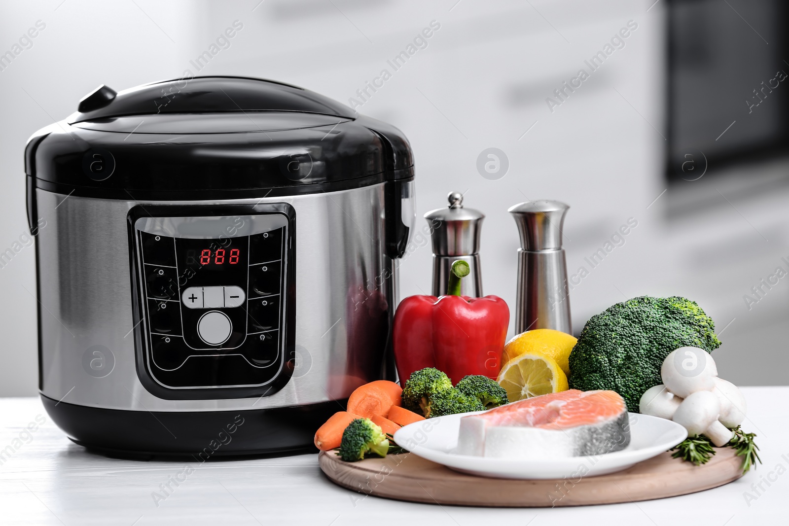 Photo of Modern multi cooker and products on table in kitchen