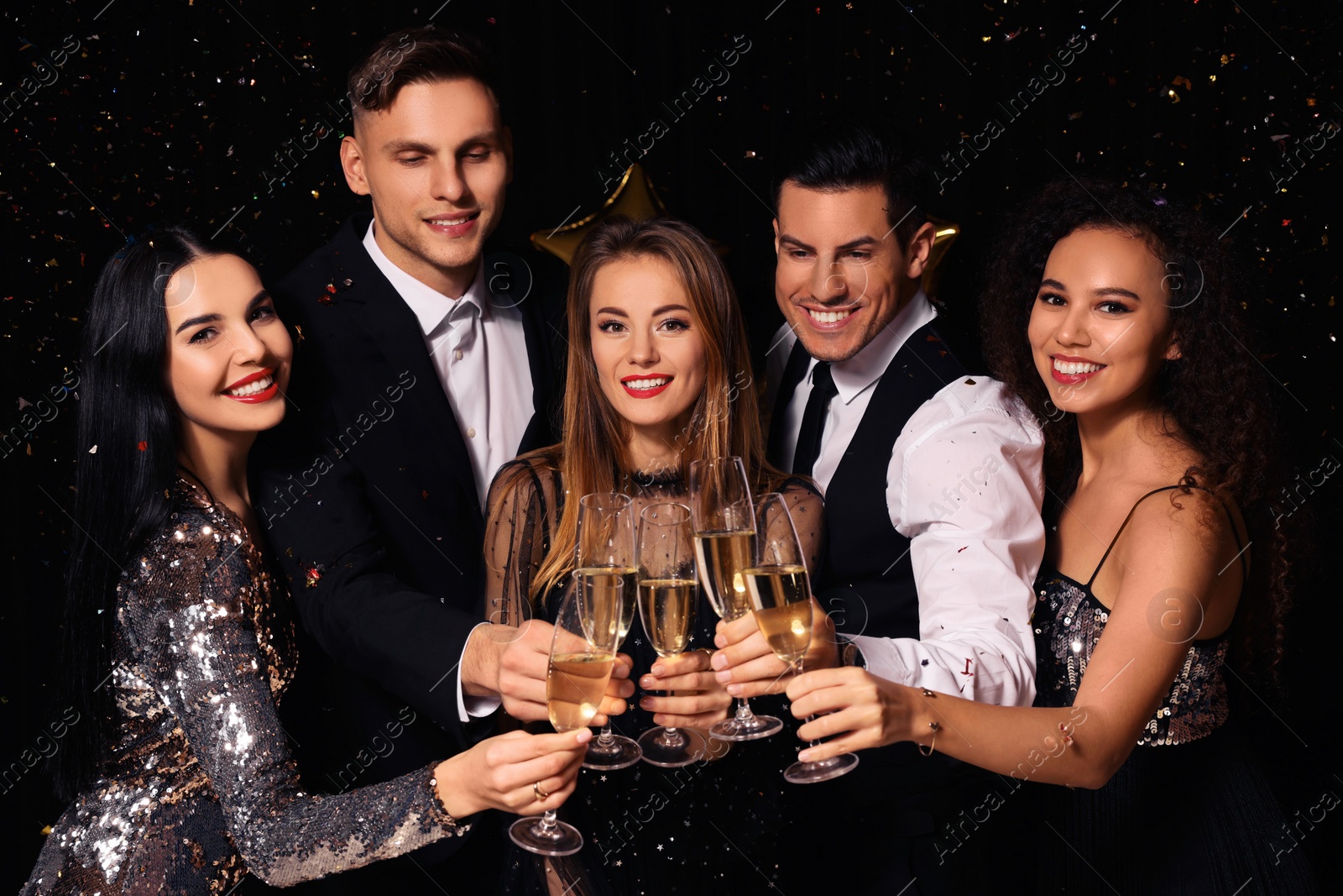 Photo of Happy friends with glasses of sparkling wine celebrating New Year on black background