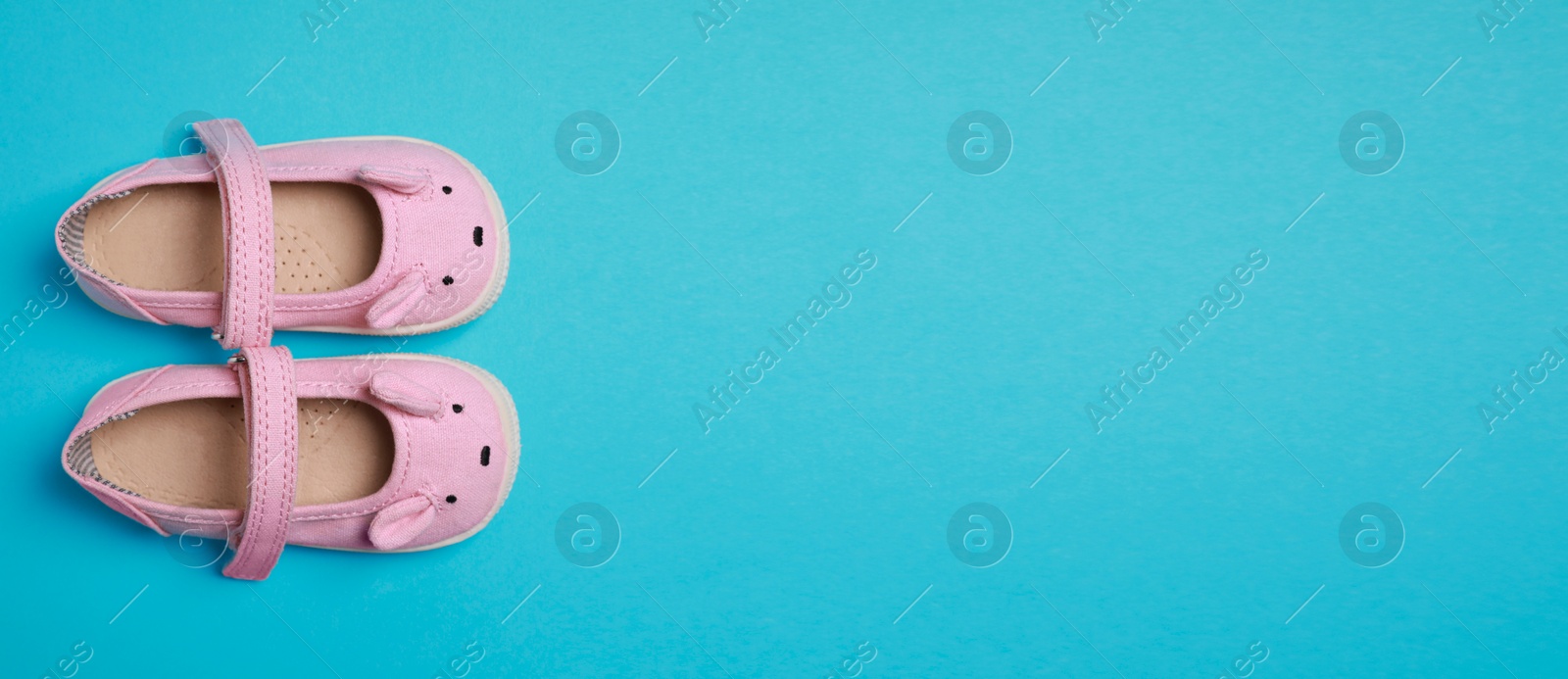 Image of Cute baby shoes on light blue background, top view. Banner design with space for text