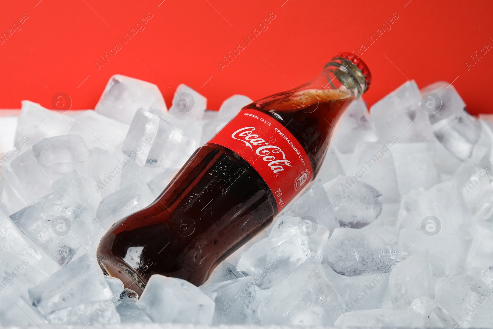 Photo of MYKOLAIV, UKRAINE - NOVEMBER 15, 2018: Bottle of Coca Cola on ice cubes against color background