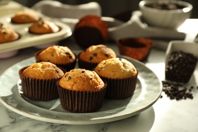 Photo of Delicious sweet muffins with chocolate chips on white marble table