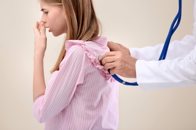 Photo of Doctor examining coughing teenage girl at clinic