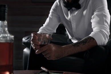 Photo of Man with glass of whiskey sitting in armchair, closeup