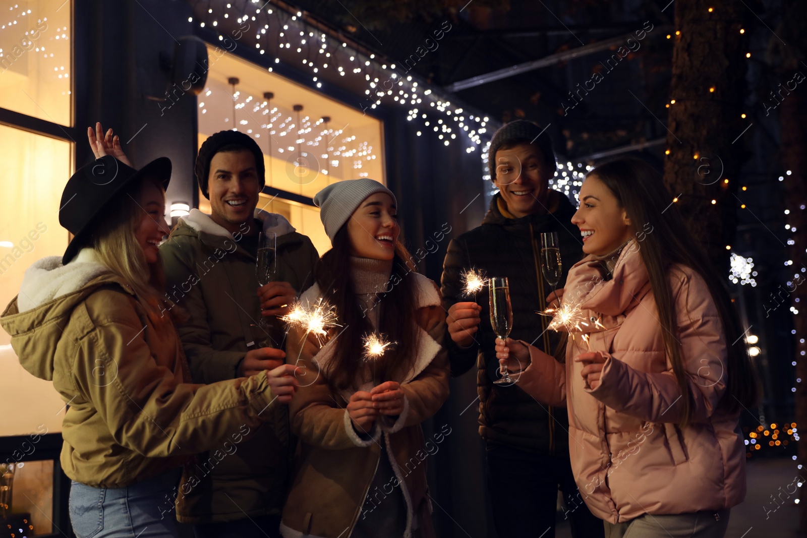 Photo of Group of happy friends with sparklers and champagne at winter fair