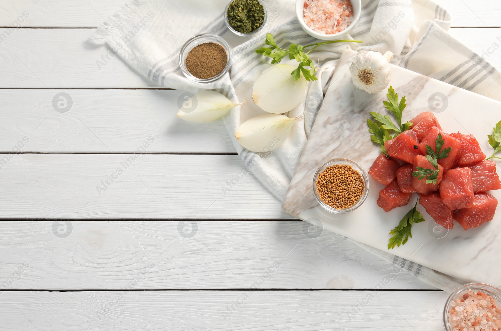 Photo of Raw beef meat and different ingredients for cooking delicious goulash on white wooden table, flat lay. Space for text