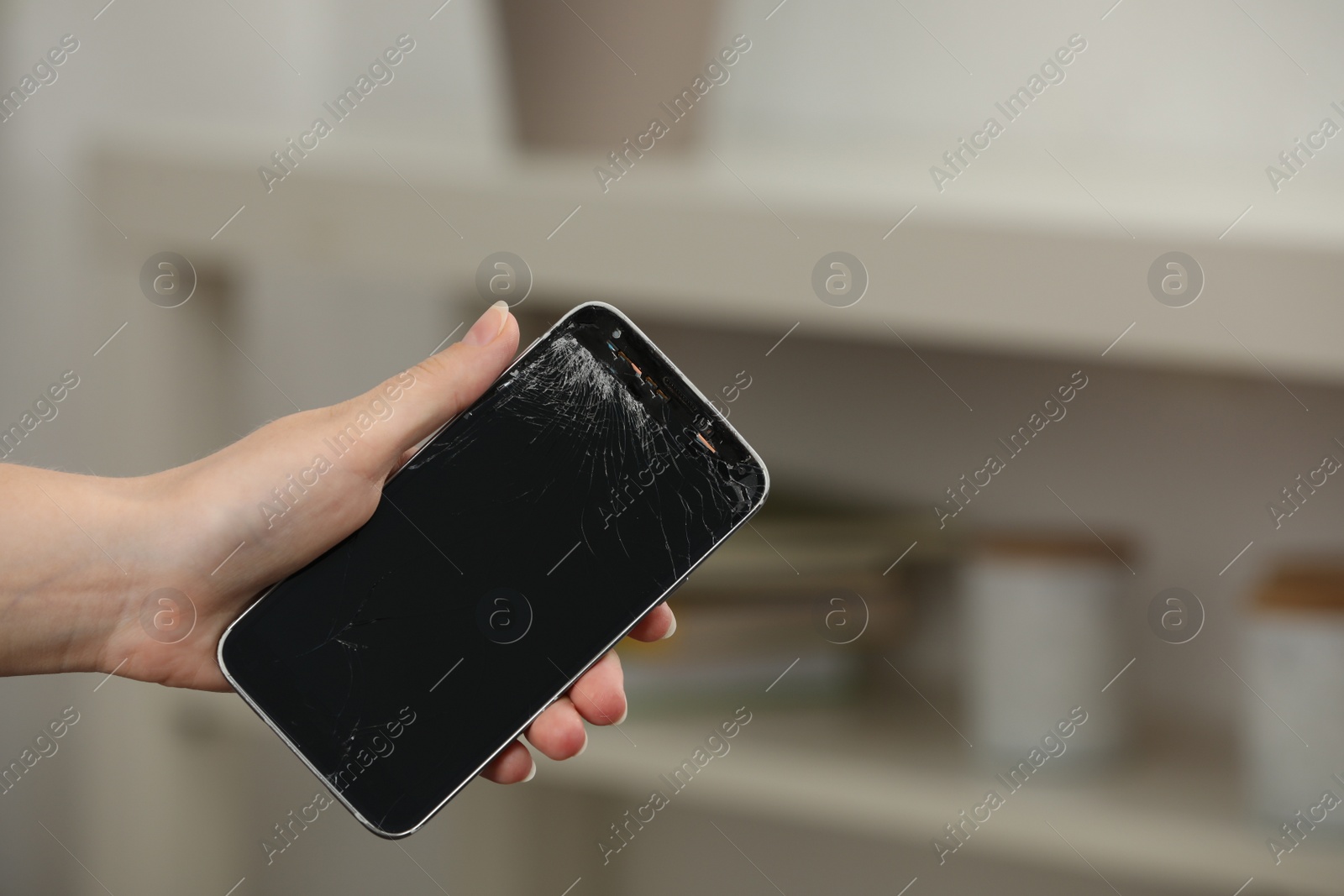 Photo of Woman holding damaged smartphone on blurred background, closeup with space for text. Device repairing