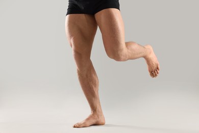 Photo of Man with muscular legs on light grey background, closeup