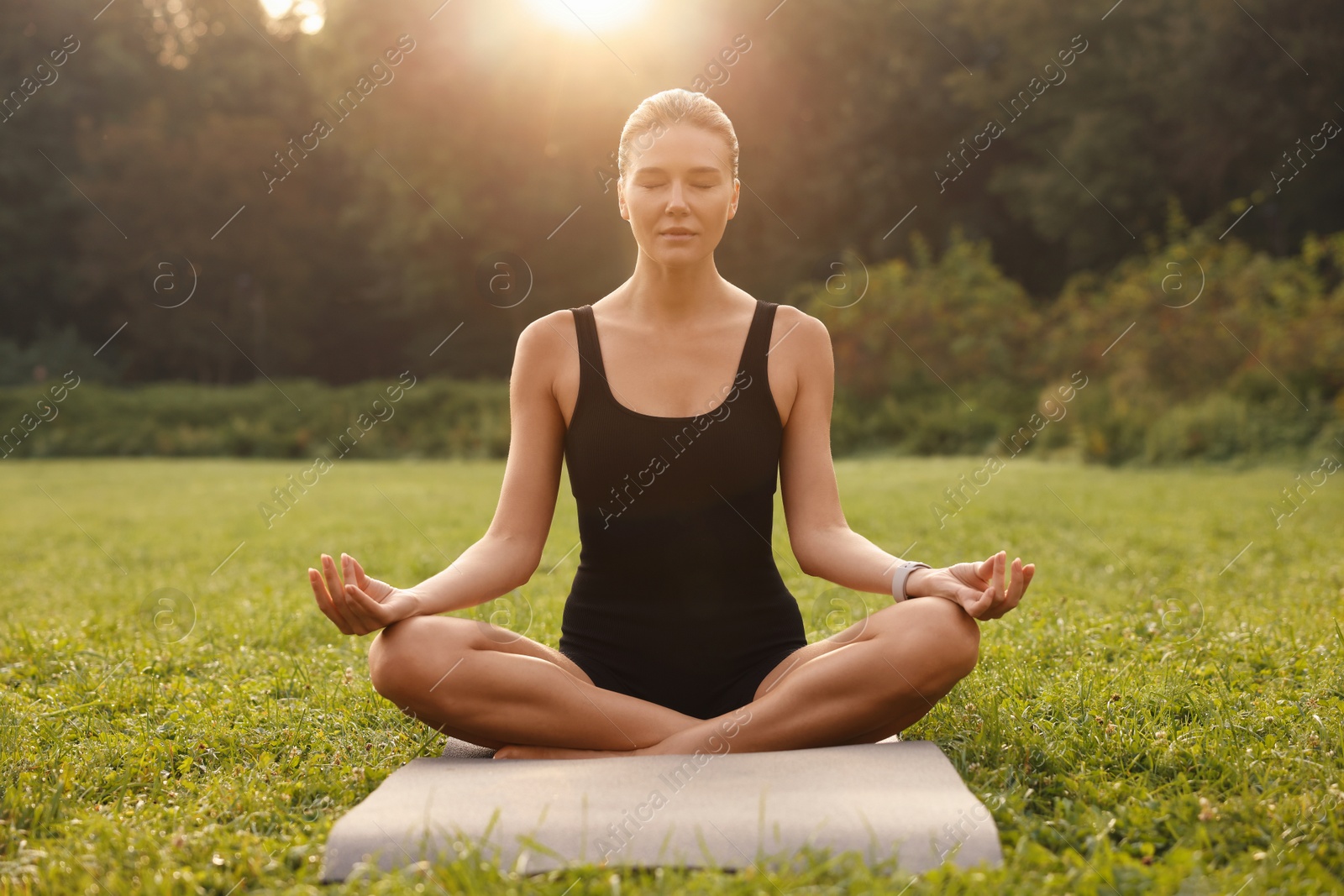 Photo of Beautiful woman practicing yoga on mat outdoors. Lotus pose