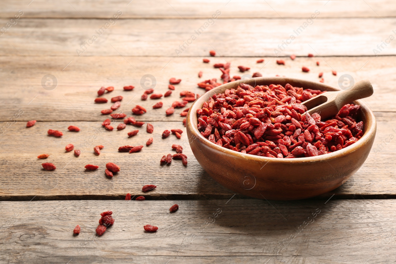 Photo of Bowl of dried goji berries and scoop on wooden table, space for text. Healthy superfood