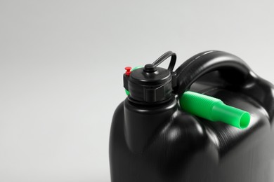 Photo of Black plastic canister with nozzle on light grey background, closeup. Space for text
