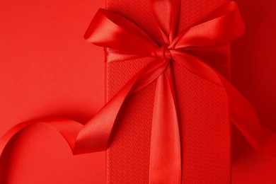 Beautiful gift box with bow on red background, top view