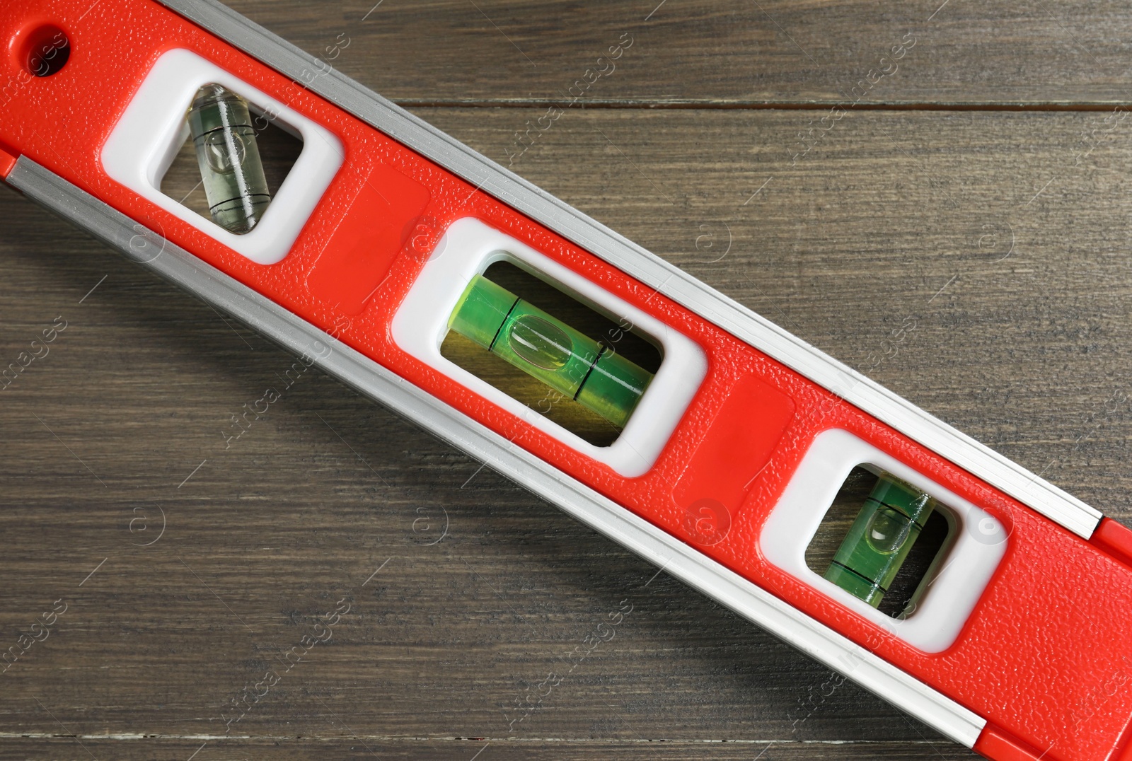 Photo of Red building level on wooden table, top view