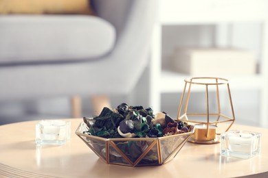Photo of Aromatic potpourri of dried flowers in bowl on wooden table indoors