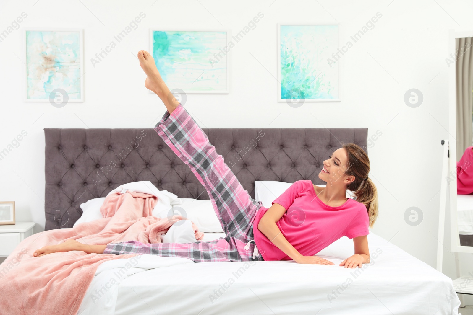 Photo of Young beautiful woman doing exercise on bed at home. Morning fitness