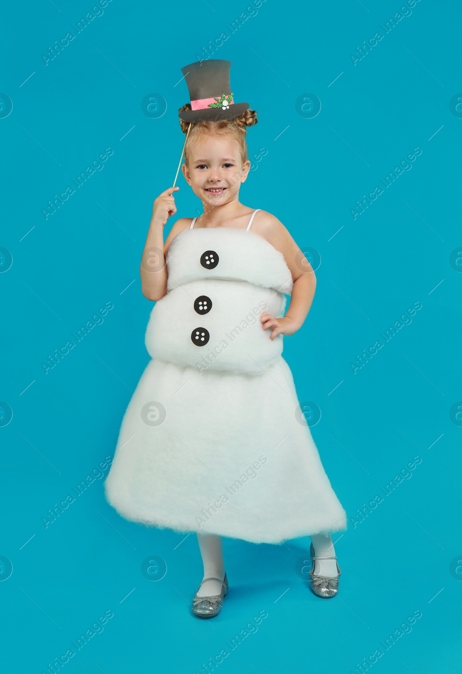 Image of Cute little girl dressed as snowman on light blue background. Christmas suit