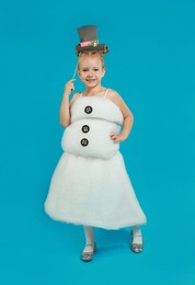 Cute little girl dressed as snowman on light blue background. Christmas suit