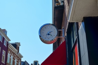 Clock attached to modern building in city on sunny day