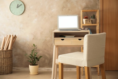 Photo of High wooden table with laptop as stand up workplace in modern interior