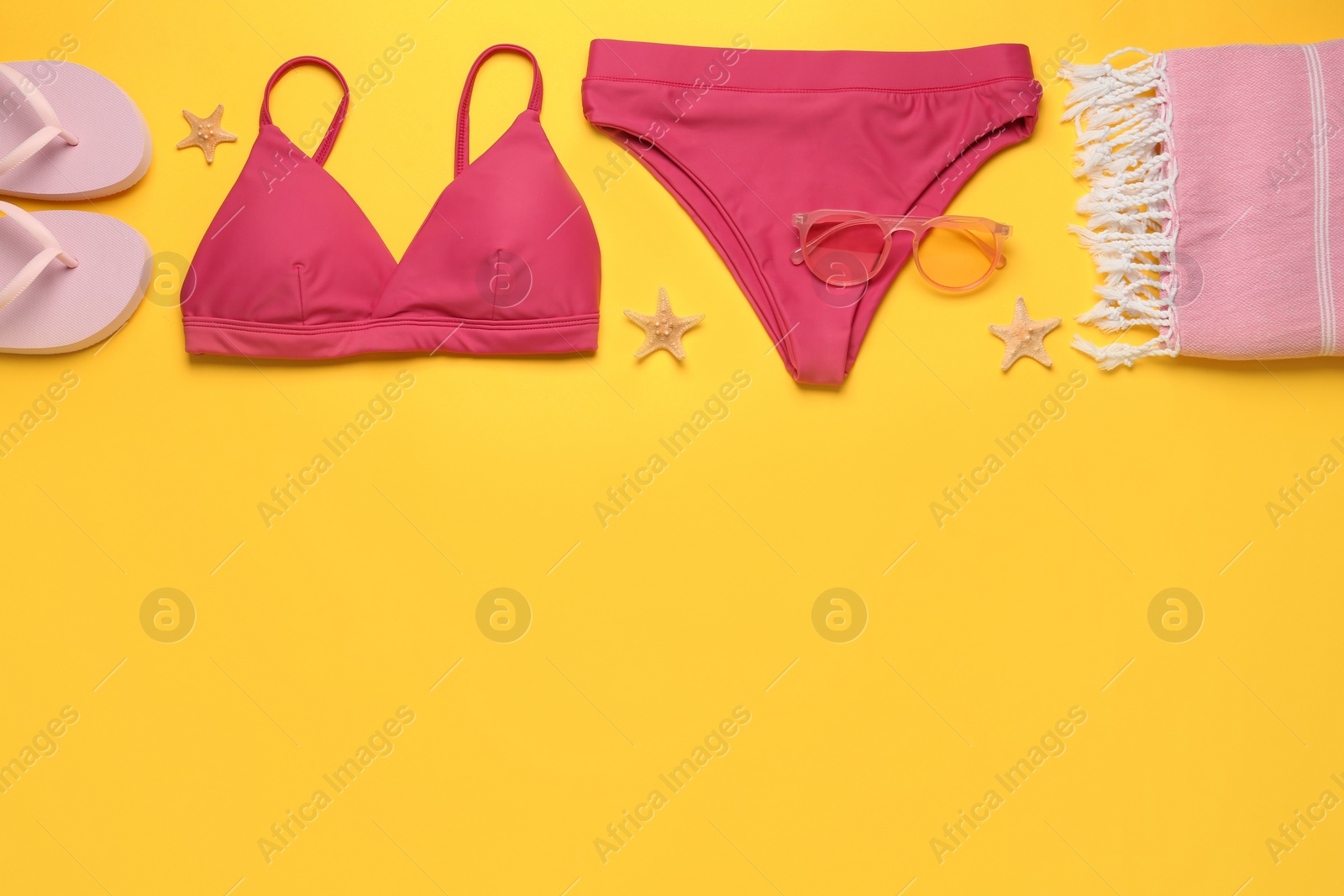 Photo of Stylish bikini and beach accessories on yellow background, flat lay. Space for text