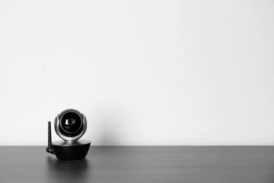 Baby monitor on wooden table, space for text. CCTV equipment