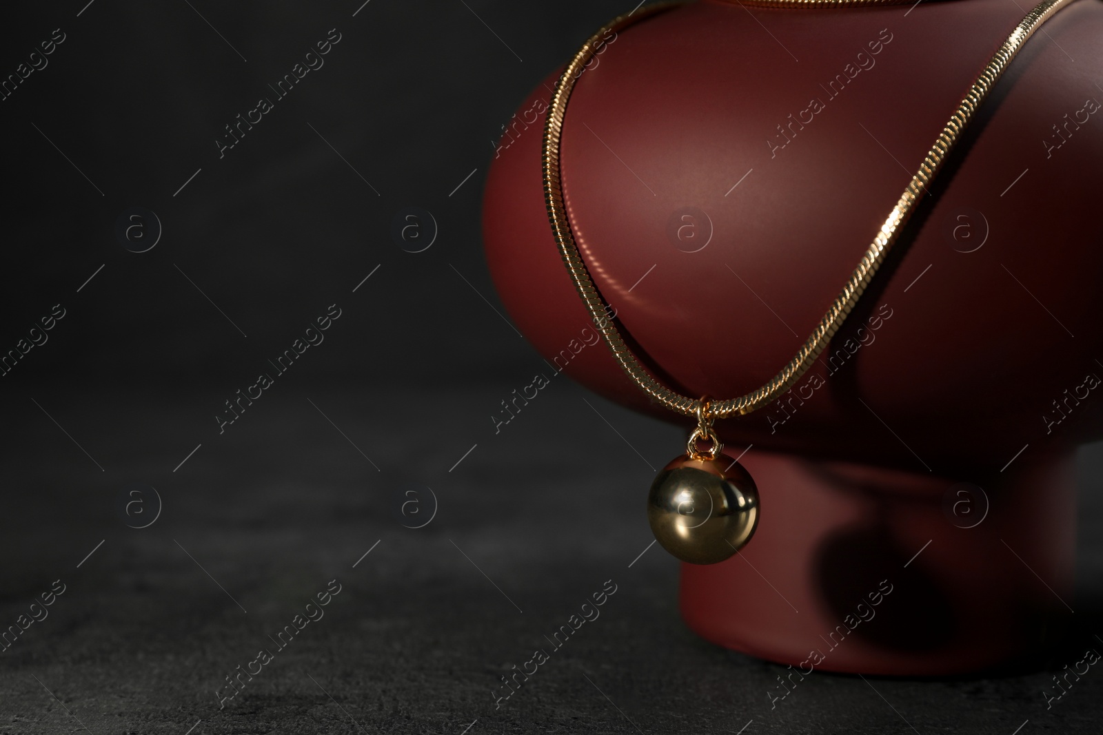 Photo of Presentation of metal chain with pendant on grey table, space for text. Luxury jewelry