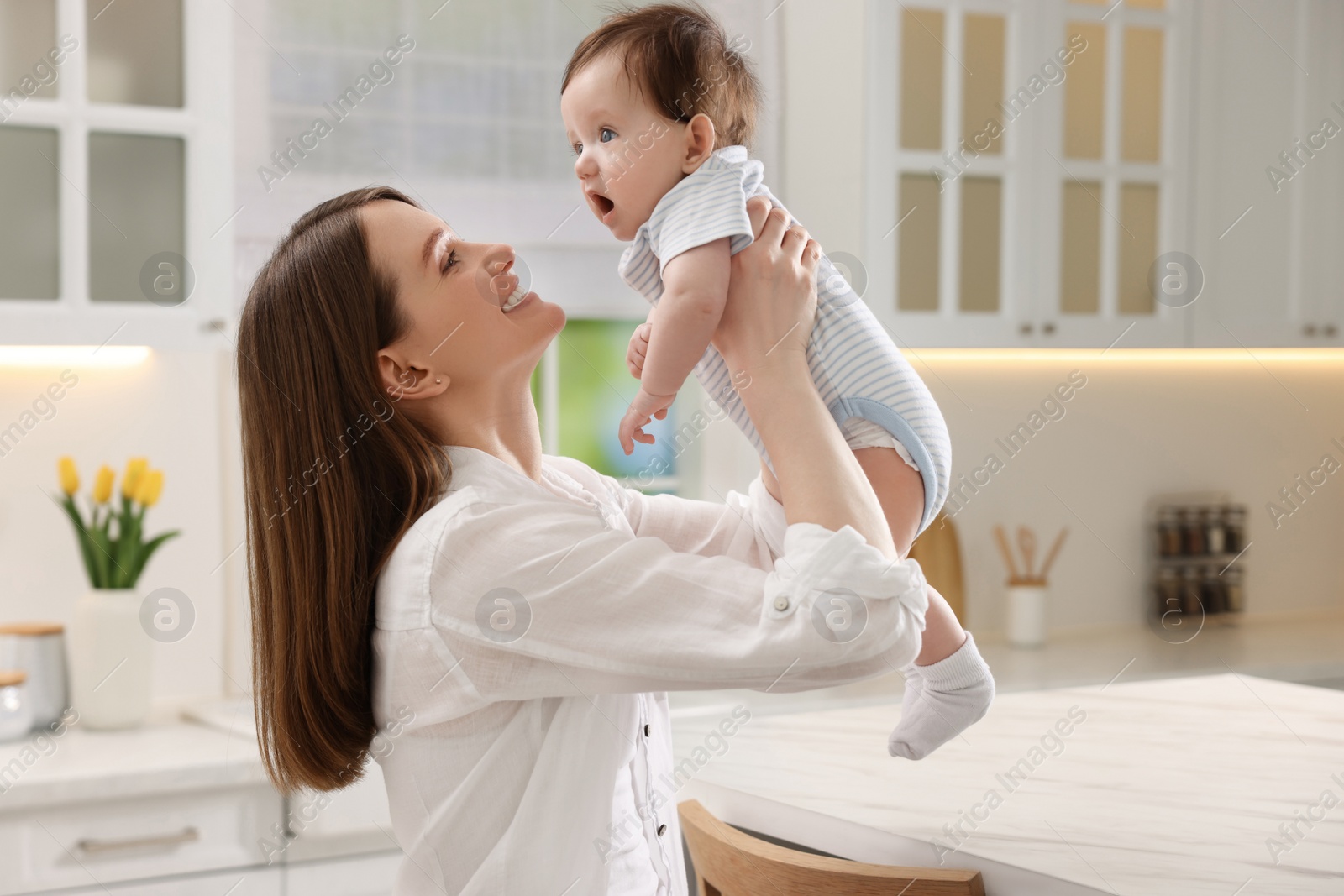 Photo of Happy mother with her little baby in kitchen at home