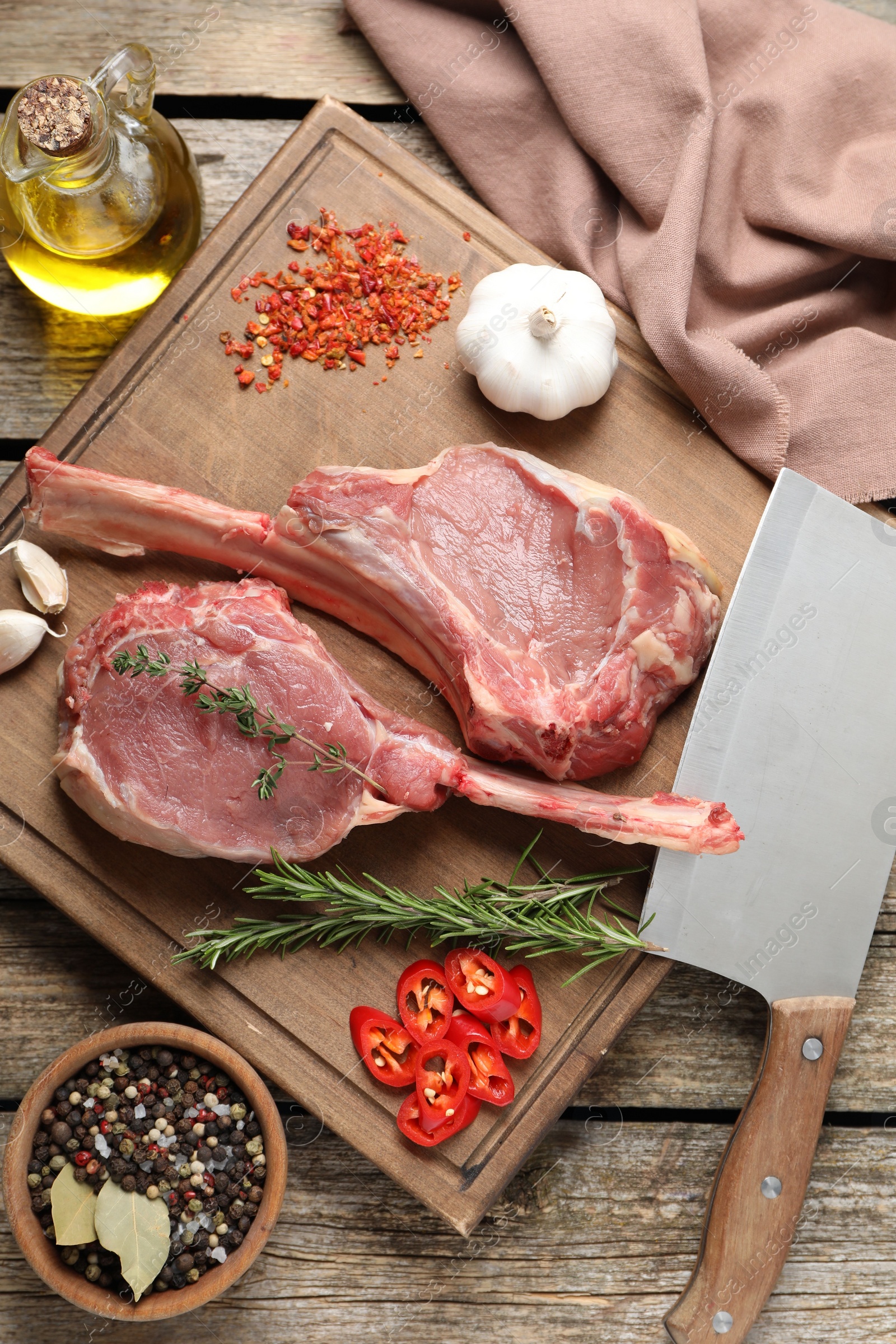 Photo of Fresh tomahawk beef cuts, butcher knife and spices on wooden table, top view