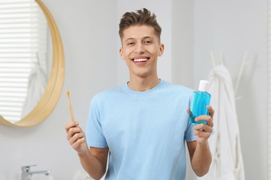 Photo of Young man with mouthwash and toothbrush in bathroom