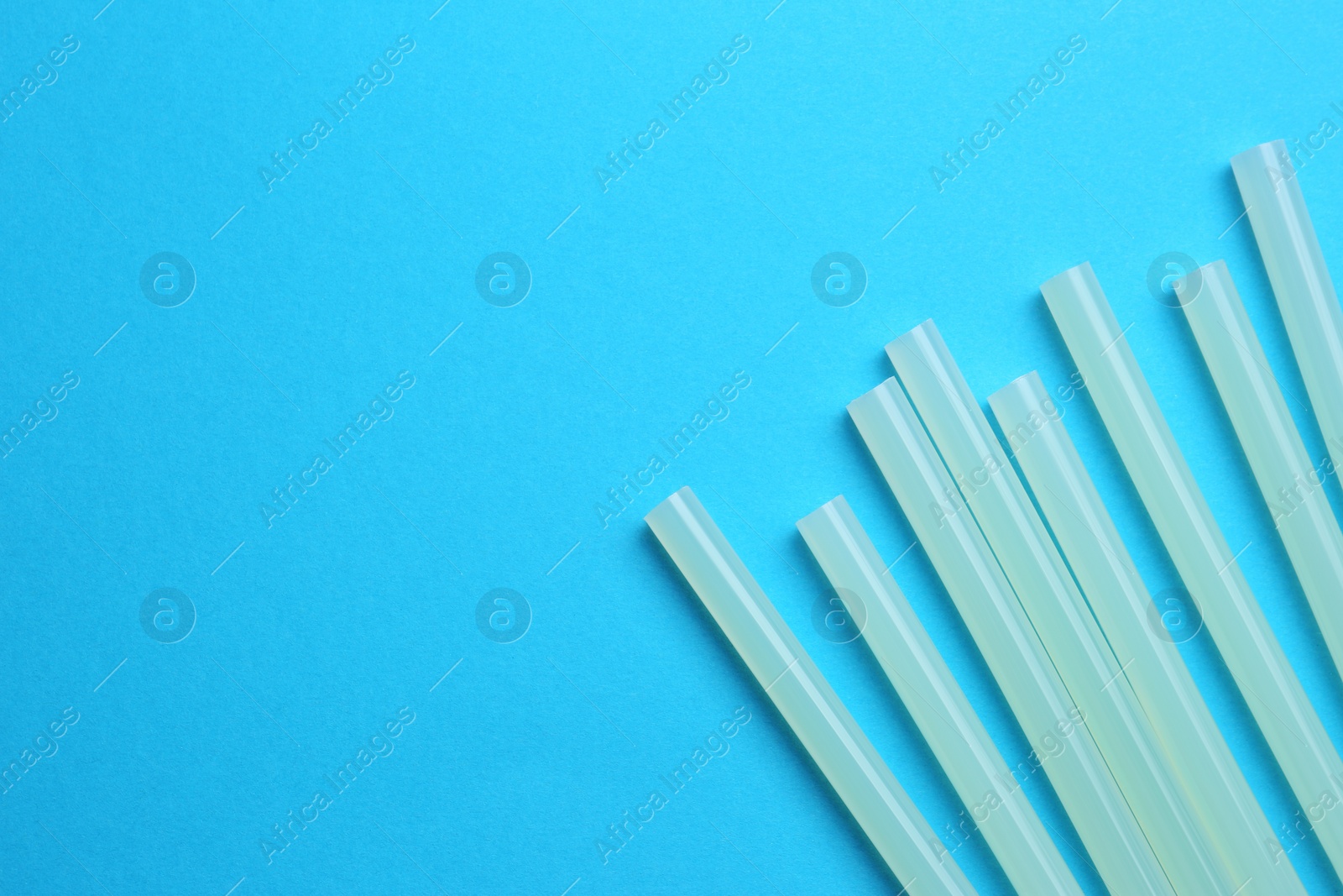 Photo of Many glue sticks on light blue background, flat lay. Space for text