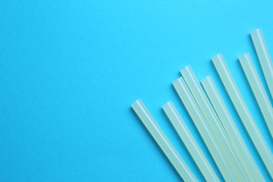 Photo of Many glue sticks on light blue background, flat lay. Space for text