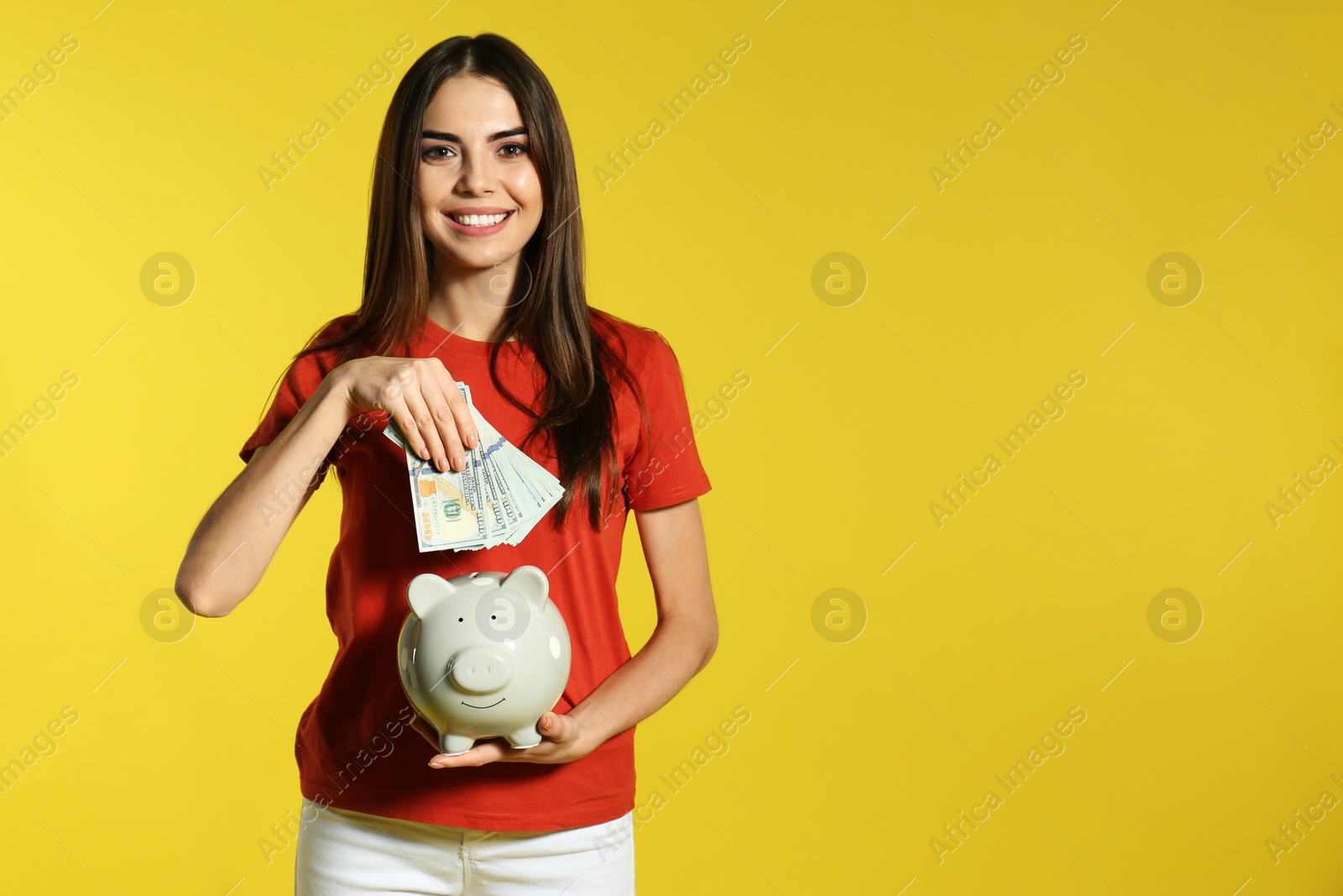 Photo of Young woman with piggy bank and money on color background. Space for text