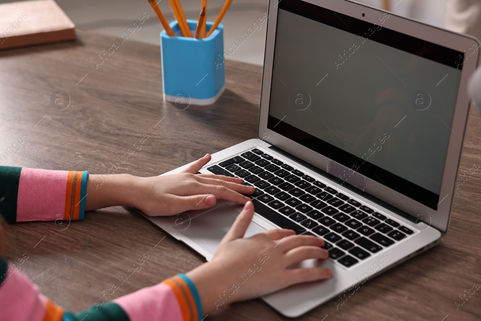 Photo of E-learning. Girl using laptop during online lesson at table indoors, closeup