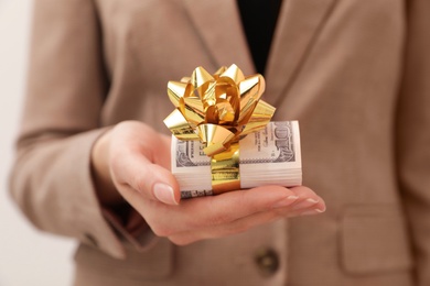 Photo of Woman holding bundle of dollars tied with ribbon, closeup