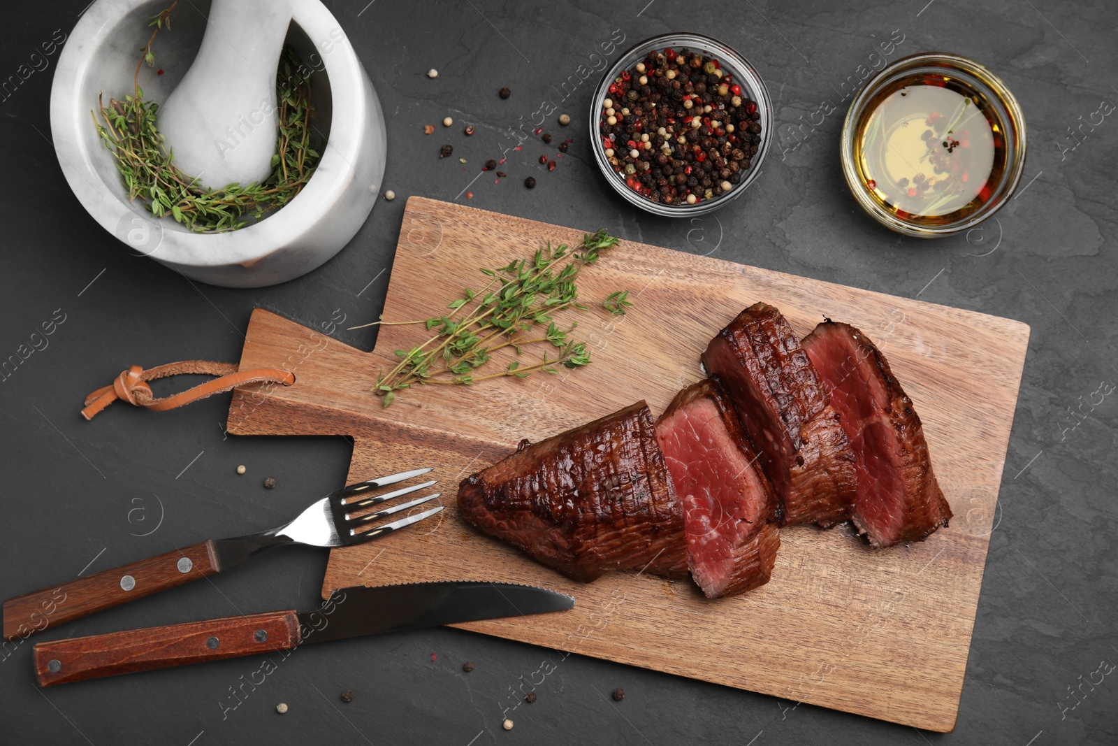 Photo of Delicious sliced beef tenderloin served on black table, top view