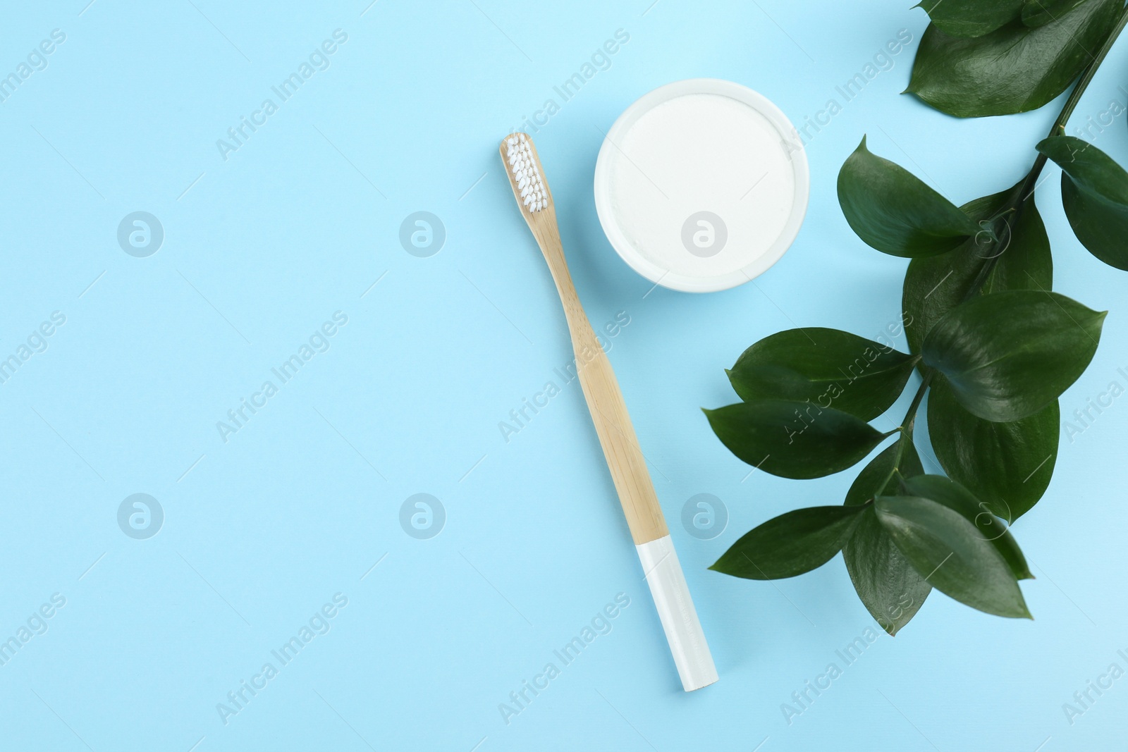 Photo of Bamboo toothbrush and bowl of baking soda on light blue background, flat lay. Space for text