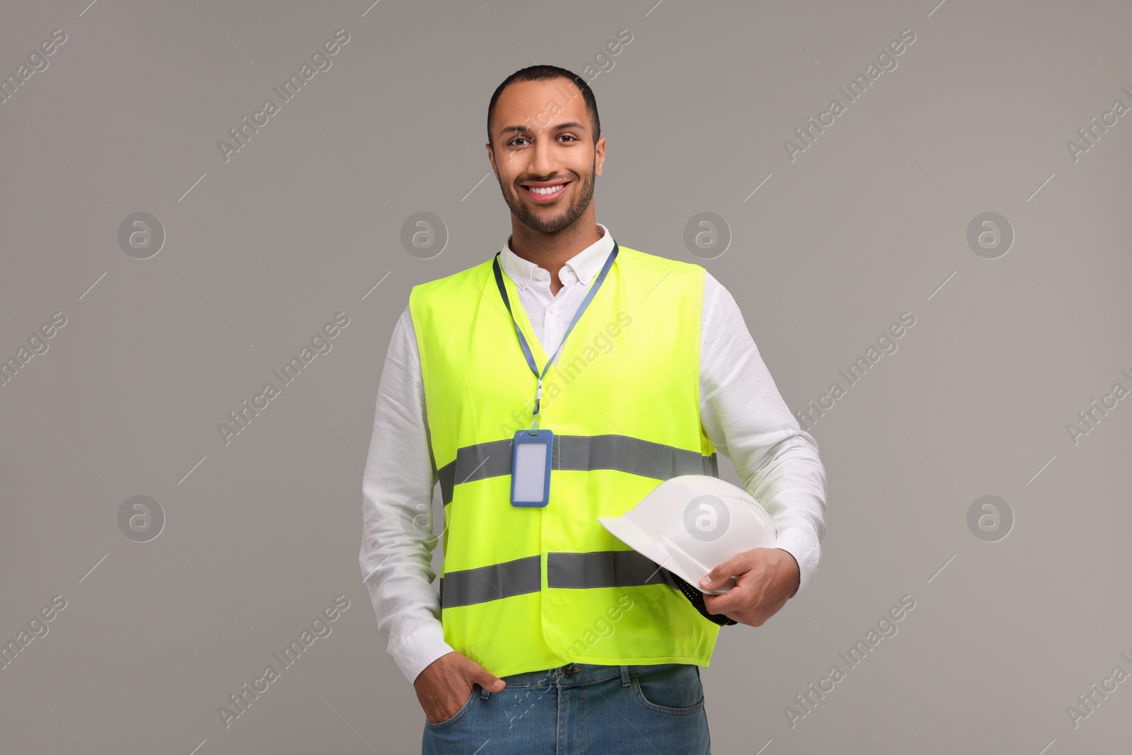 Photo of Engineer with hard hat and badge on grey background